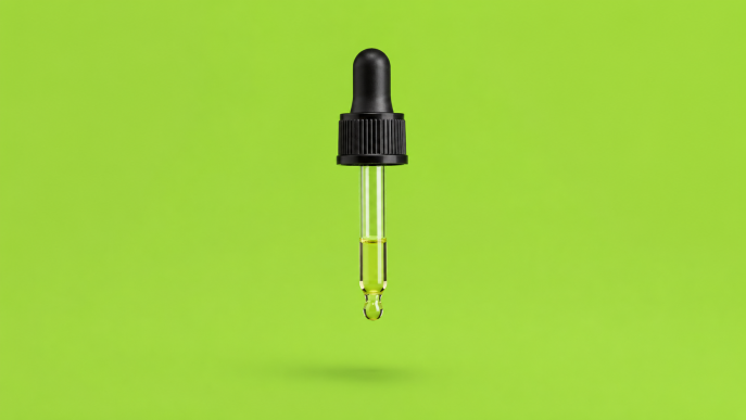 Schwarze Pipette mit durchsichtigem Glasrohr und grünlicher Flüssigkeit vor hellgrünem Hintergrund.